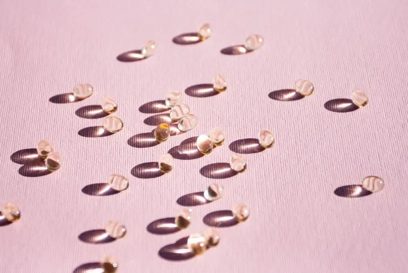 Probiotic supplements scattered on a pink surface, showcasing capsules designed for gut health.