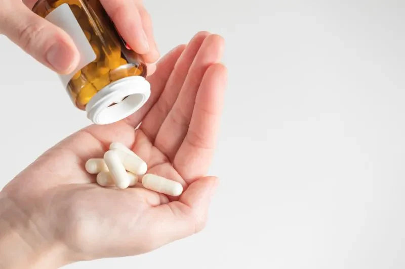 A person pouring digestive health supplements from a bottle into their hand, highlighting the importance of supplements in maintaining digestive well-being.